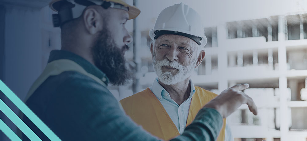 Mature construction manager talking with a mid-career construction worker