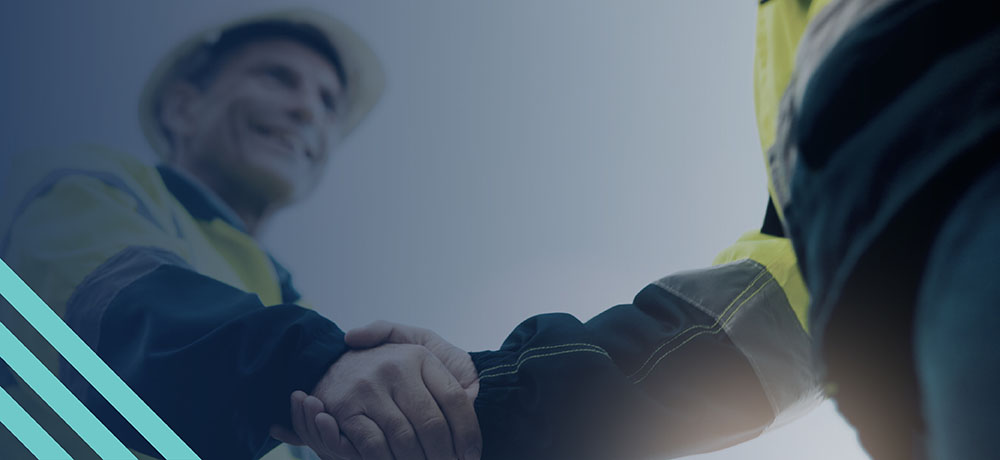 Two construction workers wearing safety gear shaking hands on jobsite