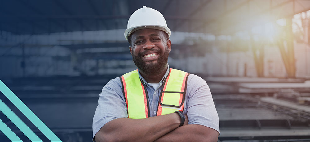 A smiling construction worker wearing a hard hat and safety vest