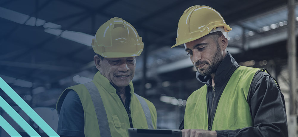 Two constructions workers in safety gear looking at a tablet