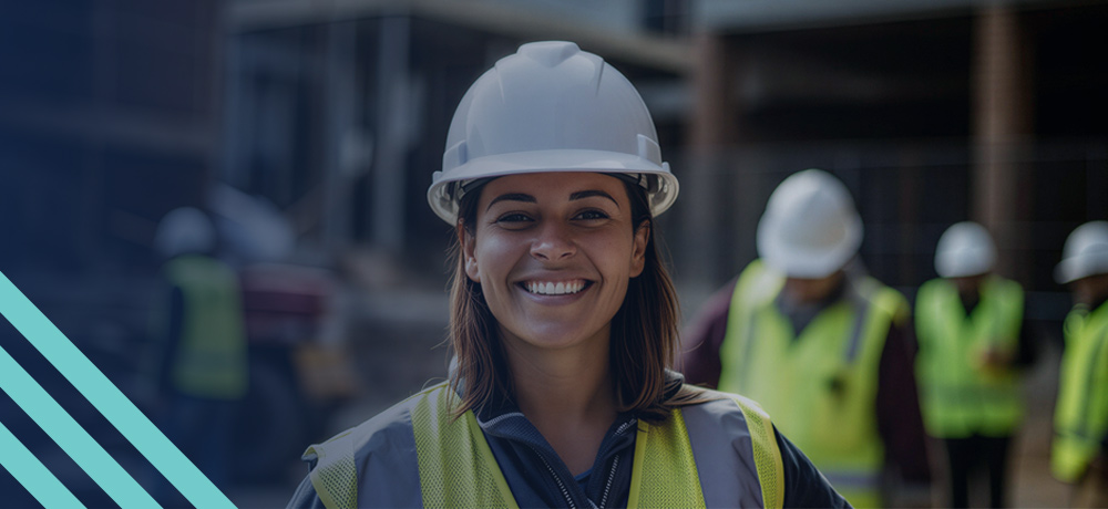 Image of a smiling construction worker wearing safety gear with other workers in the background